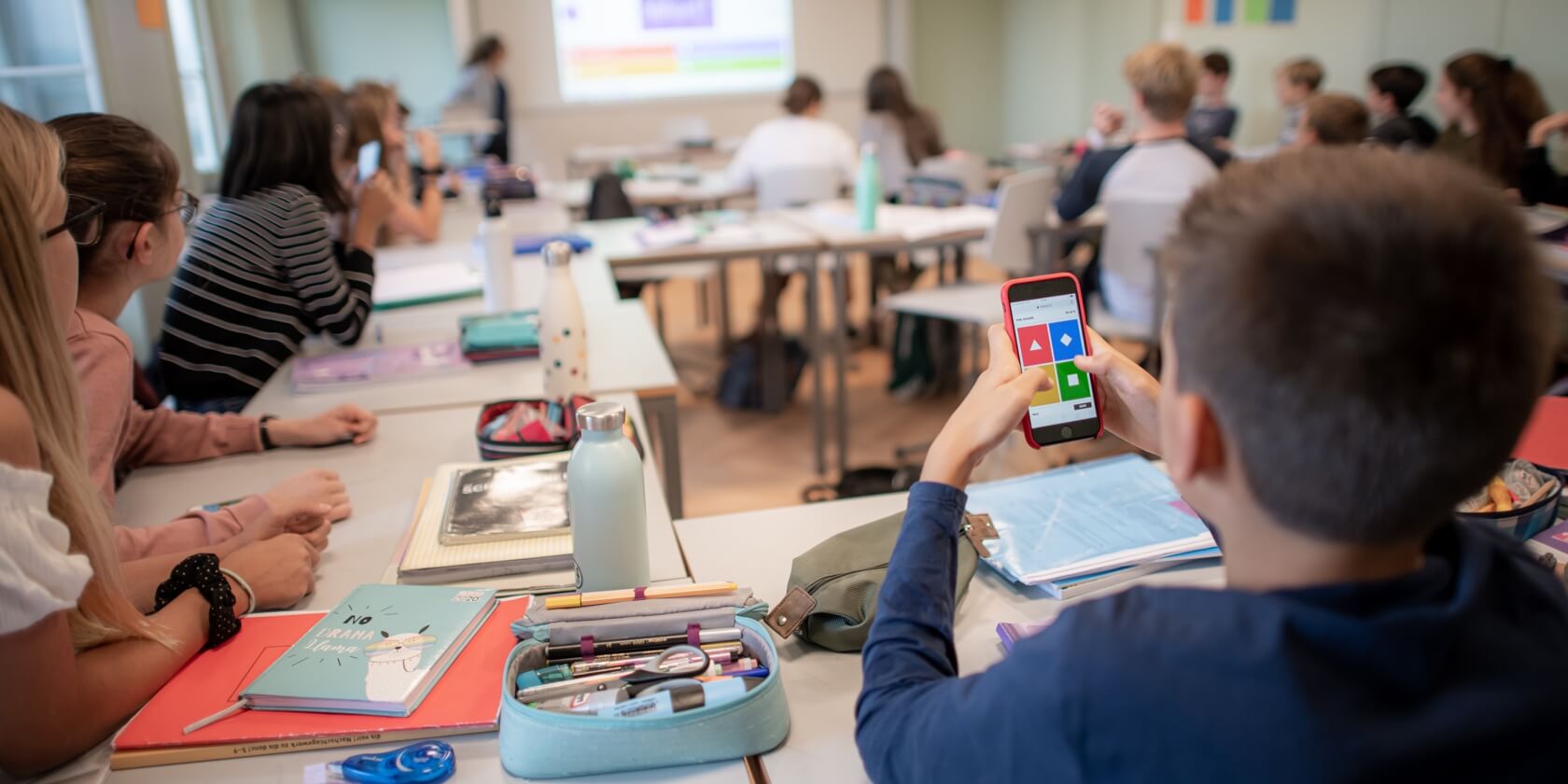 Schüler im Unterricht, Fokus auf ein Schüler mit Handy